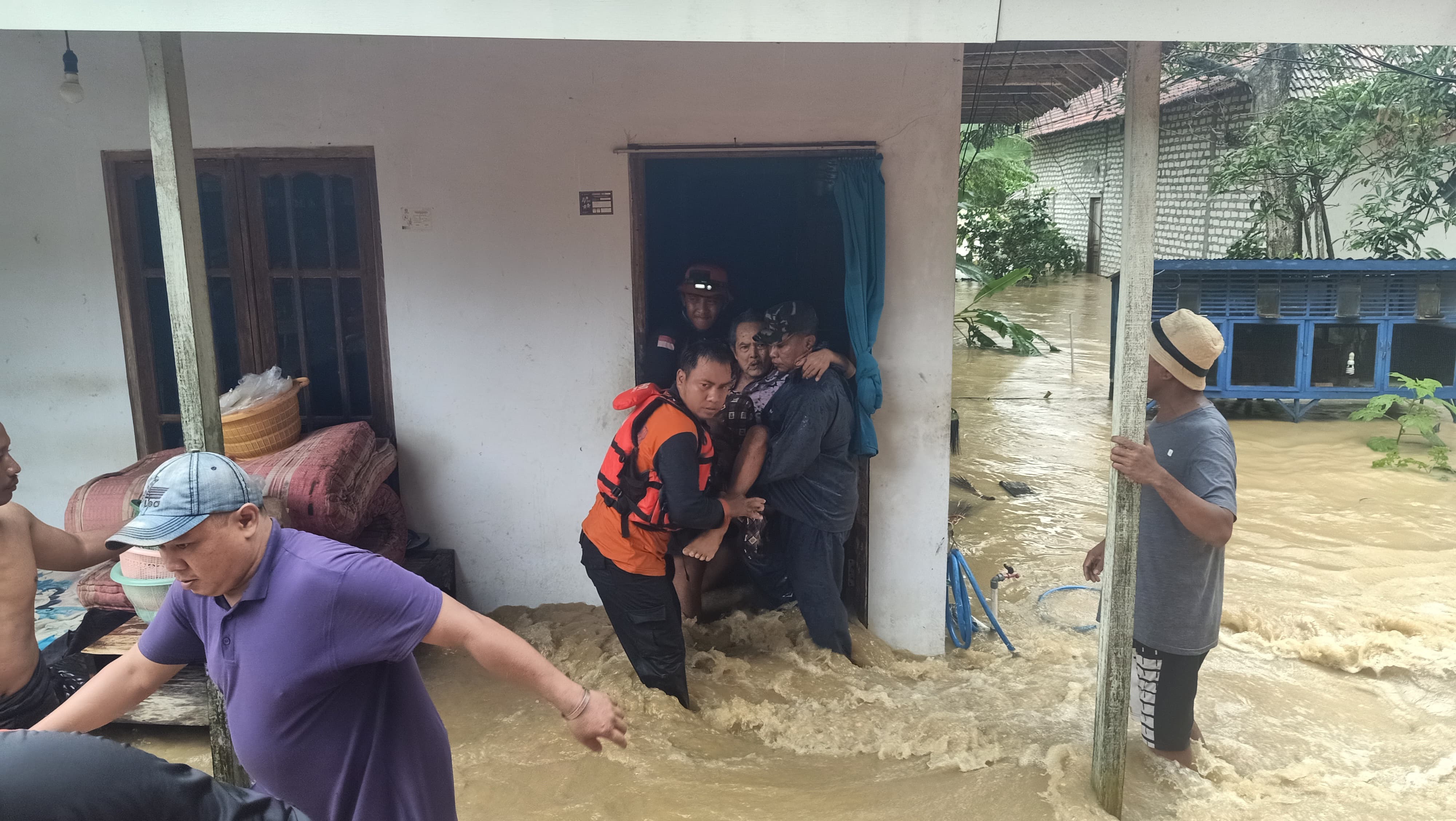 TERJEBAK: Petugas BPBD Sampang mengevakuasi warga dari dalam rumahnya yang terendam banjir di Desa Baturasang, Kecamatan Tambelangan, Sampang, Selasa (12/3). (BPBD SAMPANG UNTUK JPRM)