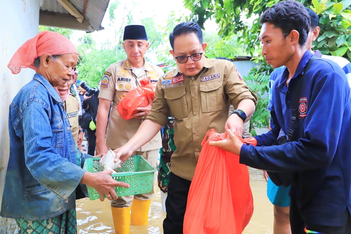 MERAKYAT: Pj Gubernur Jatim Adhy Karyono (berkacamata) menyerahkan nasi bungkus kepada korban banjir di Kecamatan Blega, Bangkalan, Rabu (13/3).
