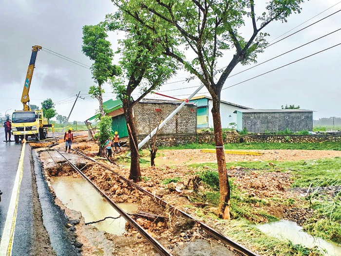RUSAK: Petugas PLN menangani tiang listrik yang miring di dekat bangunan yang miring akibat banjir di tepi jalan nasional Kecamatan Jrengik, Sampang, Rabu (13/3). (UBAIDILLAHIR RA&rsquo;IE/JPRM)