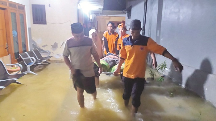 EMPATI: Seorang warga di Kelurahan Jungcangcang, Pamekasan, digotong menggunakan tandu untuk diungsikan di lokasi yang aman, Selasa (12/3). (BPBD UNTUK JPRM)