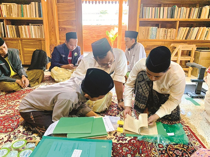 DITELITI: Koordinator Nahdlatut Turots Utsman Hasan (pegang kitab) sedang menelaah sejumlah kitab di Pesantren Sembilangan Kramat Bangkalan. (NAHDLATUT TUROTS UNTUK JPRM)
