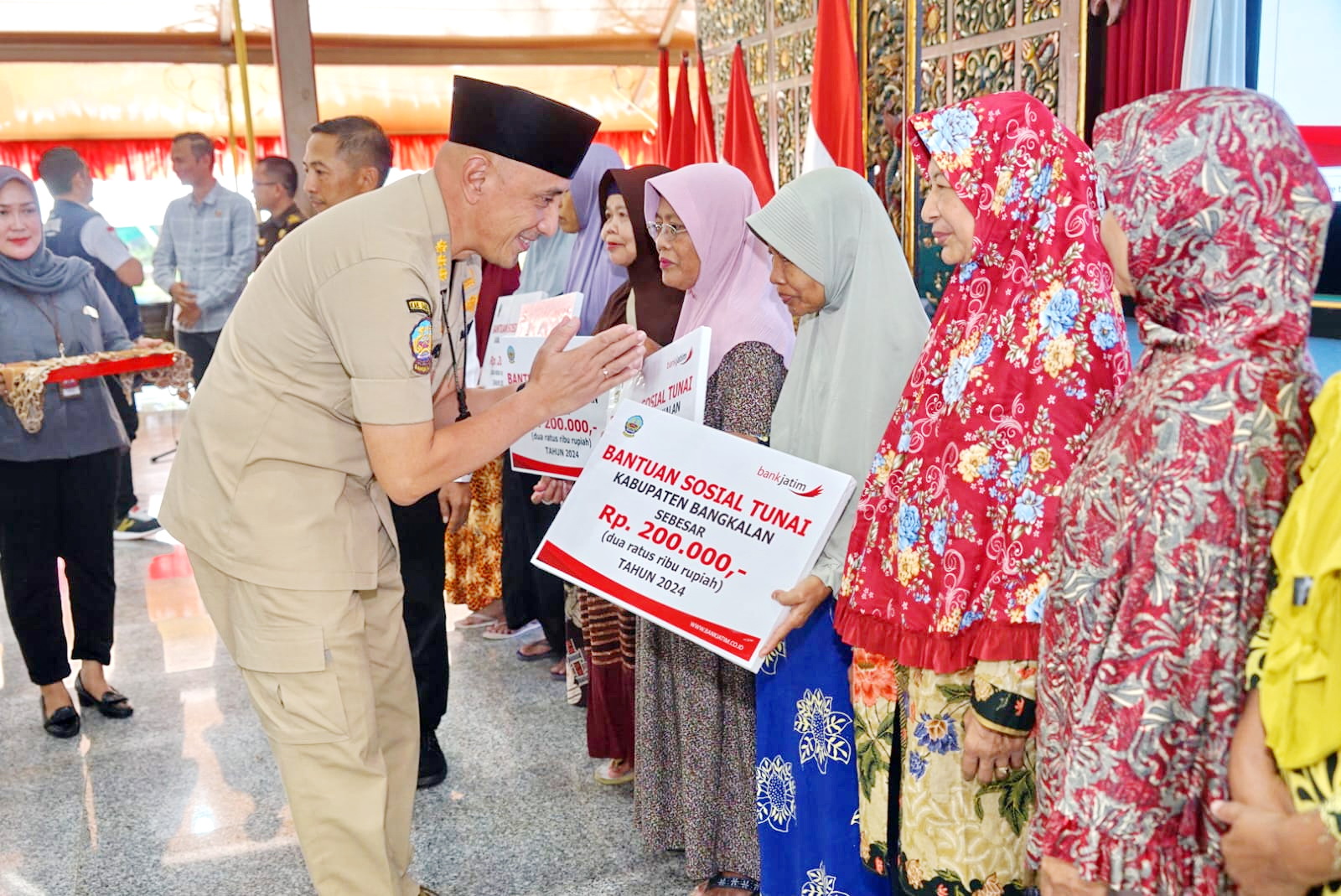 TEGAS: Pj Bupati Bangkalan Arief M. Edie menyerahkan bansos tunai kepada KPM di Pendopo Agung, Selasa (19/3).