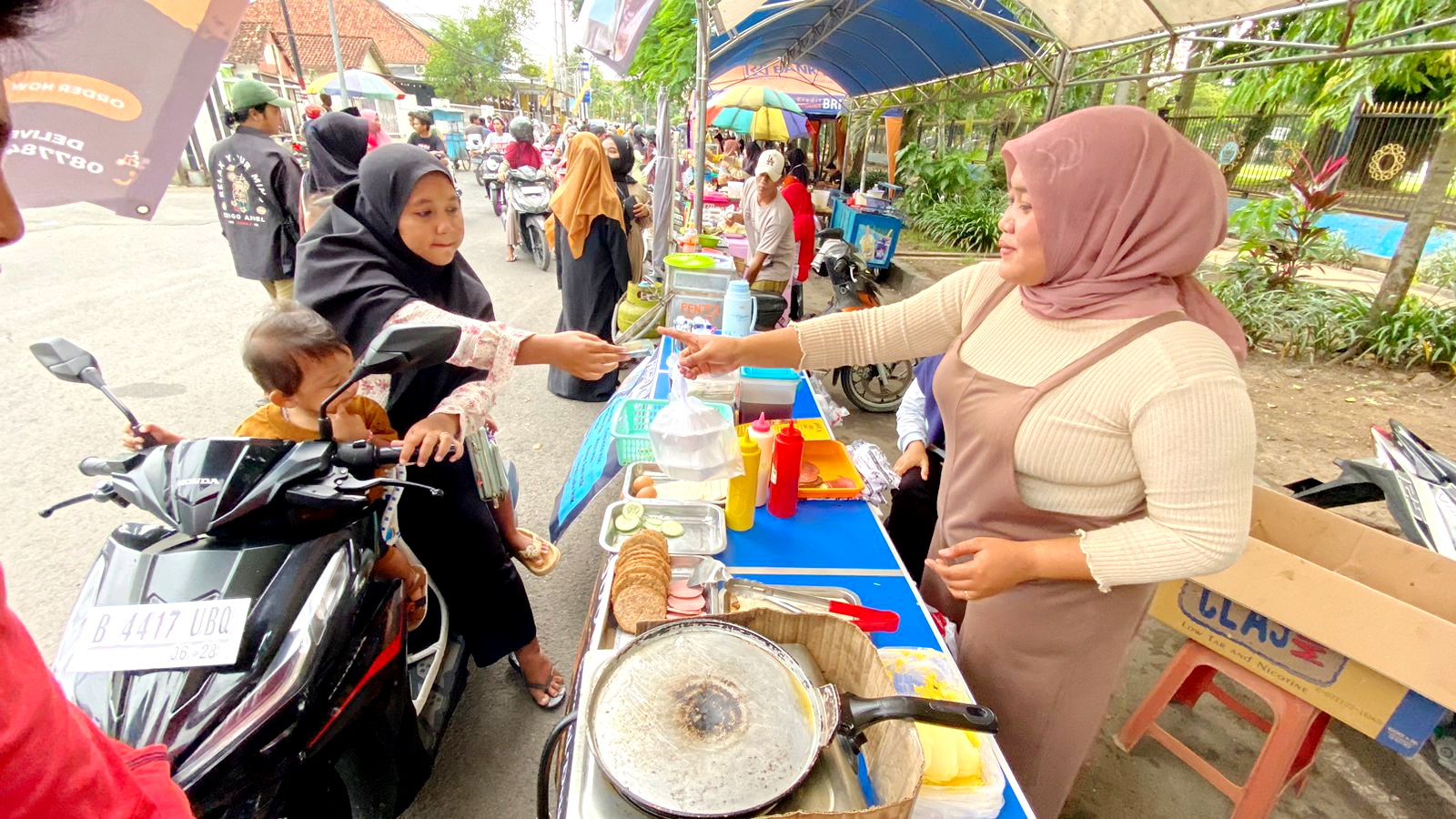 MAKANAN SIAP SAJI: Pekerja Burgerku Ismawati sedang melayani pembeli di area Bazar Takjil Ramadan Bangkalan, Minggu (17/3). (AYU LATIFAH/JPRM)