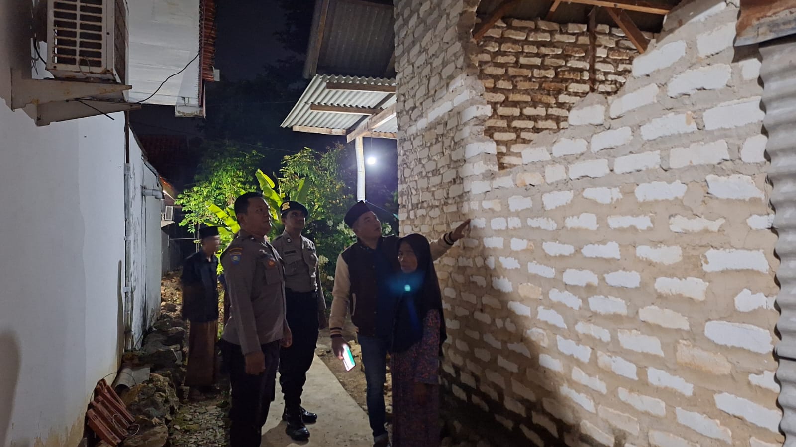 RUSAK: Kapolsek Larangan Iptu Moh. Kadarisman mendatangi rumah Sani korban akibat gempa di Desa Panaguan, Larangan, Pamekasan pada Jumat malam (22/3).