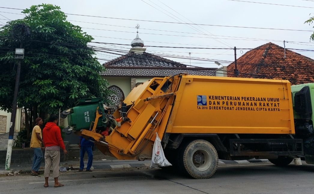HARUS BERSIH: Petugas menaikkan sampah dari tong sampah yang ada di Jalan Trunojoyo, Kota Sampang, untuk diangkut ke tempat pembuangan akhir, Sabtu (16/3).