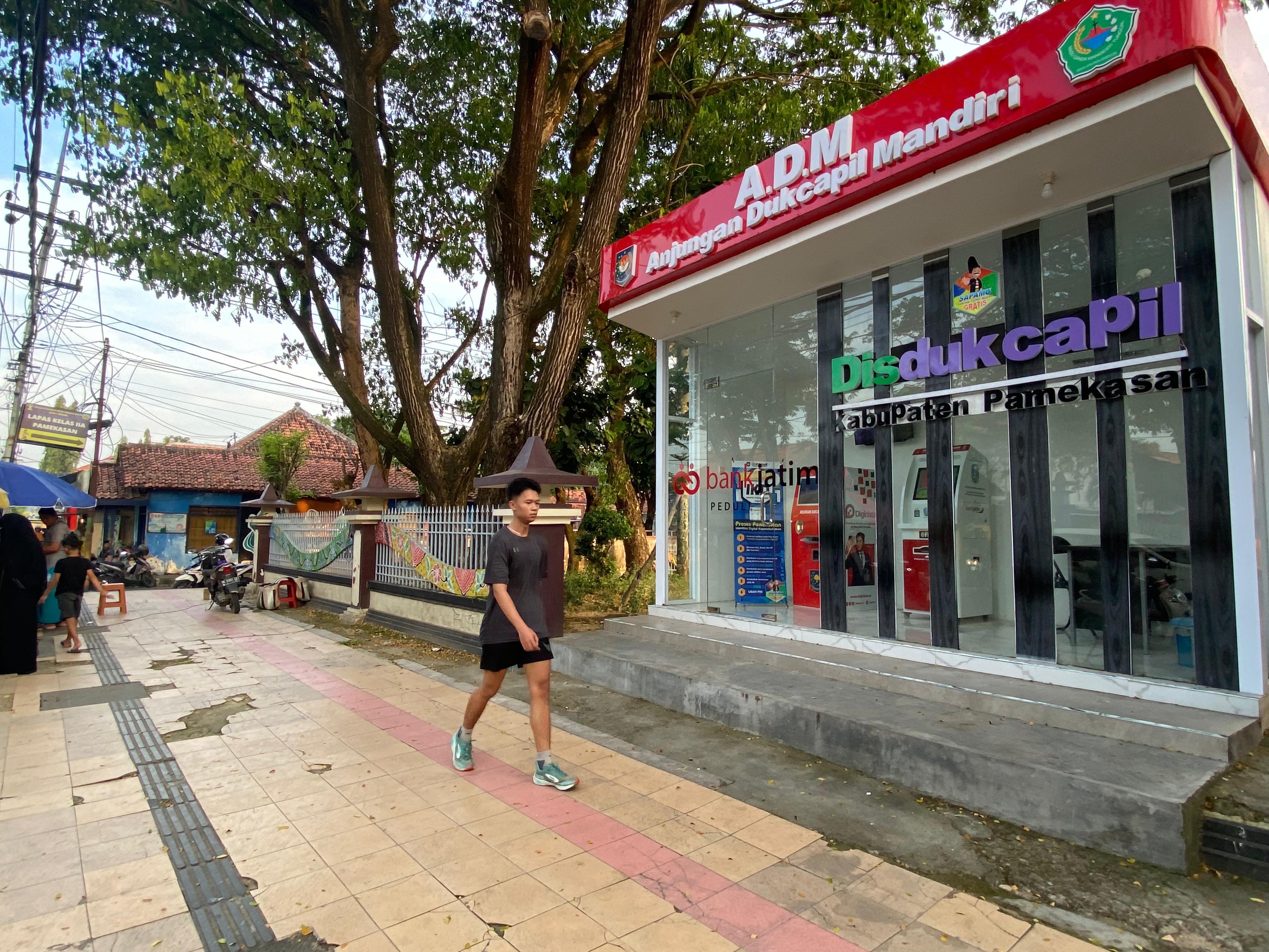 SANTAI: Pemuda berjalan di depan ADM Disdukcapil Pamekasan di Jalan Kabupaten, Kelurahan Bugih, Pamekasan, Rabu (27/3). (LAILIYATUN NURIYAH/JPRM)