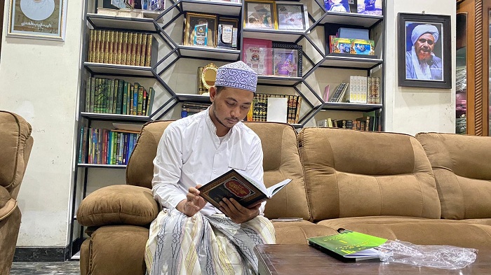 KARAMAH: Lora Ismail Al Ascholy sedang membaca kitab karyanya di kediamannya di Kelurahan Demangan, Bangkalan, Sabtu (16/3). (AYU LATIFAH/JPRM)