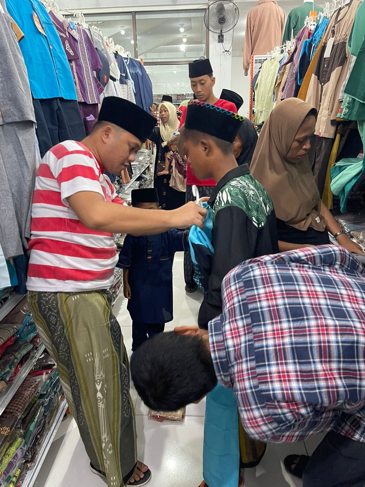 TELATEN: Anggota DPR RI  Slamet Ariyadi memasangkan pakaian kepada salah seorang anak yatim di dalam toko Perintis Jaya Swalayan.
