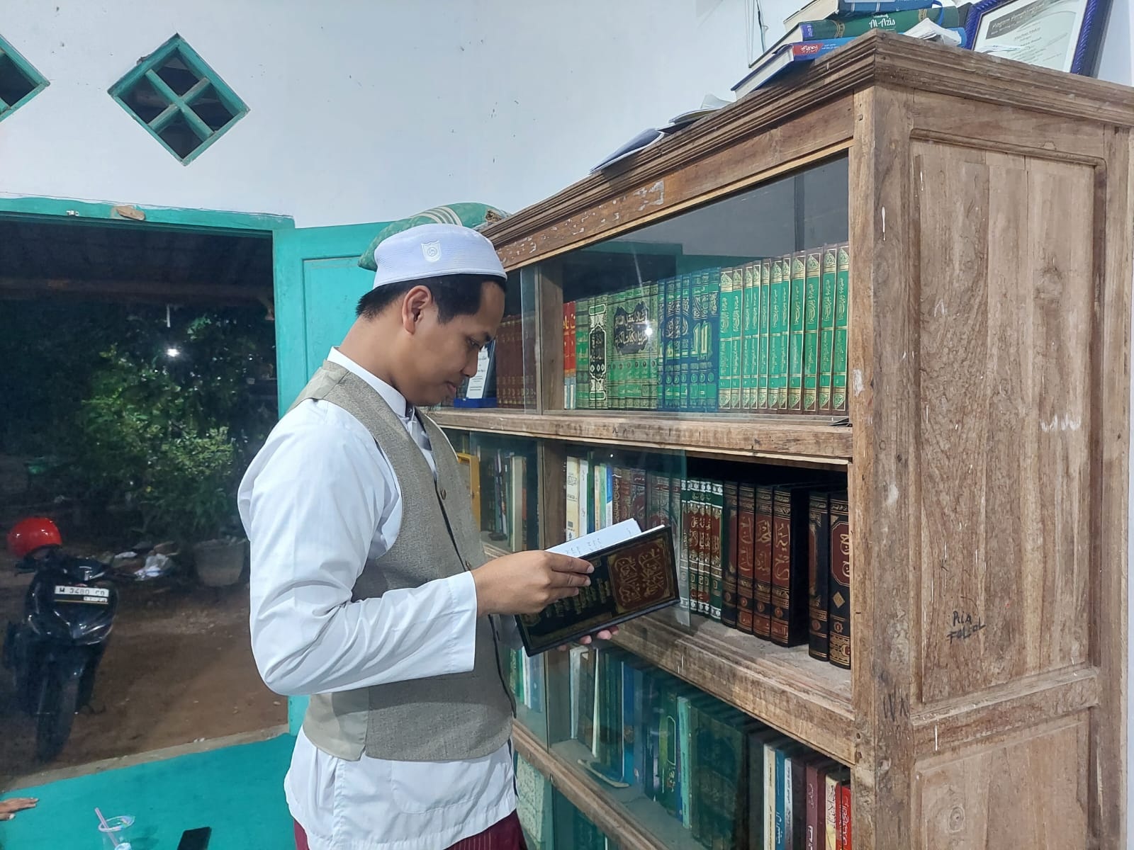 MELEK DIGITAL: Lora Mukhtar Makin Yahya membaca kitab koleksi pribadinya di Desa Lomaer, Kecamatan Blega, Bangkalan, Senin (1/4). (ZEINAL ABIDIN/JPRM)
