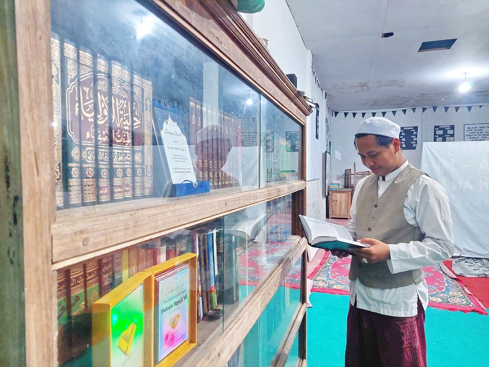 GENIUS: Lora Mukhtar Makin Yahya membaca koleksi kitab di Desa Lomaer, Keamatan Blega, Bangkalan, Senin (1/4). (ZEINAL ABIDIN/JPRM)