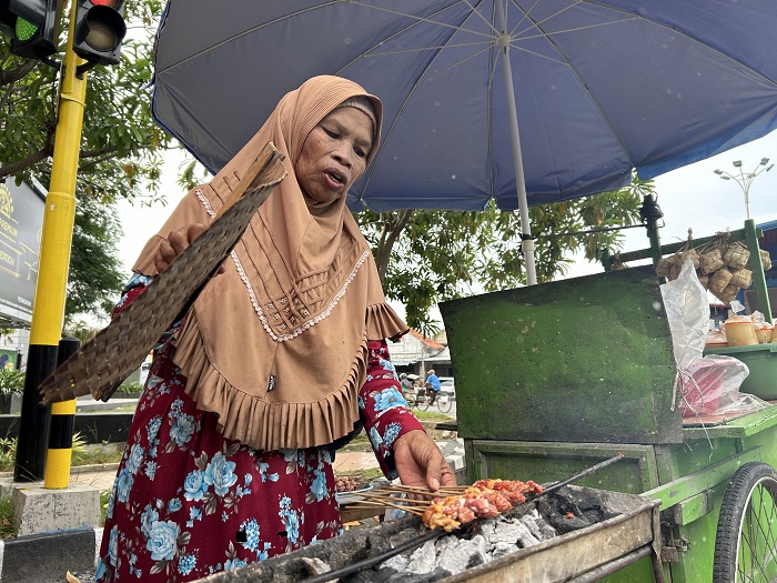 BARA API: Misriah sedang memanggang sate di Bangkalan Rabu (27/3). (VIVIN AGUSTIN HARTONO/JPRM)