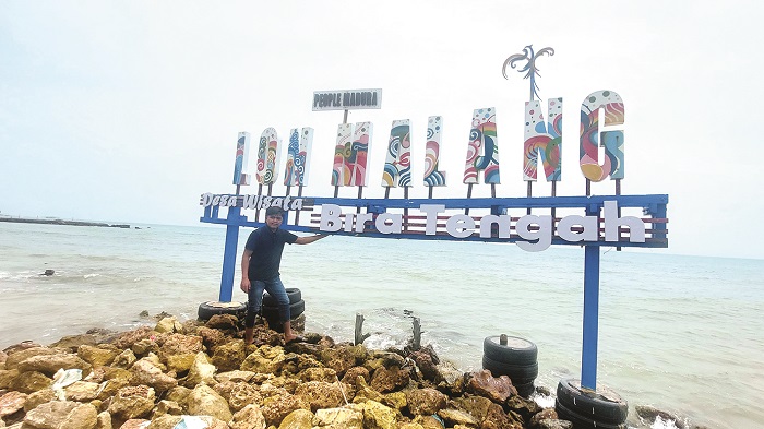 IKONIK: Pengunjung berada di dekat papan nama wisata Pantai Lon Malang, Desa Bira Tengah, Kecamatan Sokobanah, Sampang, Sabtu (6/4). (JUNAIDI PONDIYANTO/JPRM)