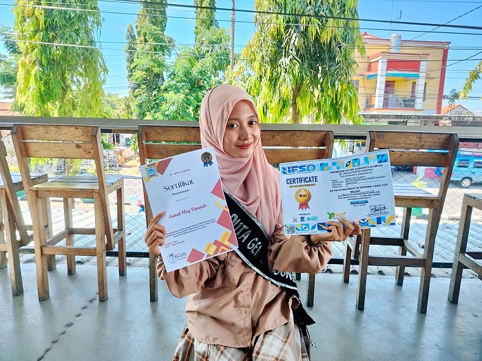 MEMBANGGAKAN: Arinal Haq Fauziyah memegang piagam penghargaan Indonesian Future Scientists Olympics di salah satu kafe di Desa Panglegur, Kecamatan Tlanakan, Pamekasan, Sabtu (20/4).