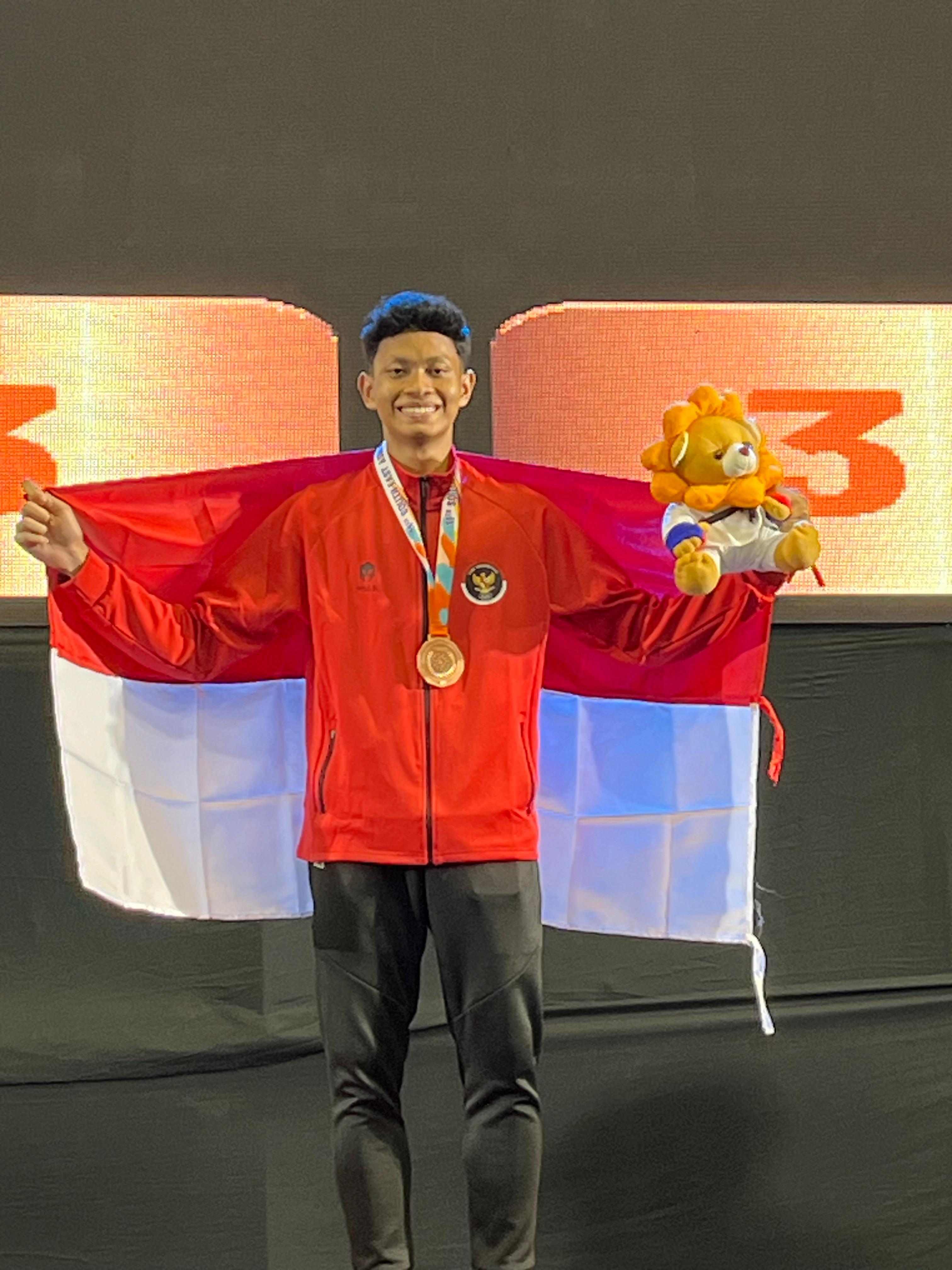 MEMBANGGAKAN: Atlet Karate Pamekasan Brillyan Bayu Erlangga membentangkan bendera Indonesia usai meraih medali perunggu SEAKF Championship 2024 di Thailand, Jumat (26/4). (DOJO BINA SATRIA UNTUK JPRM)