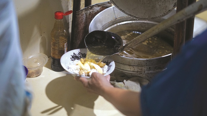 SEDAP: Muhammad Rido&rsquo;i menuangkan kuah soto ke dalam mangkuk di warungnya, Jumat (6/4). (ABRAR GHAZY HARDIAN/JPRM)