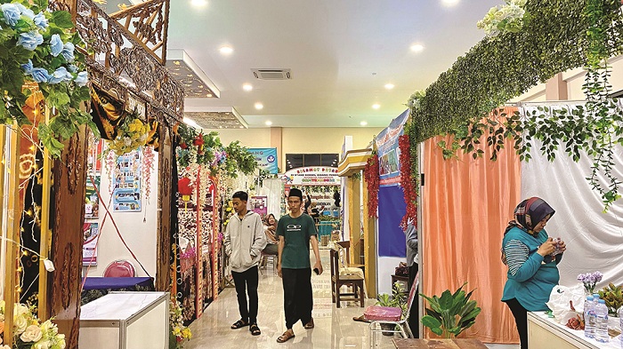 PERSIAPAN: Sejumlah peserta sedang sibuk menata barang di stan yang berjejer rapi di Gedung Sentra IKM Bangkalan yang menjadi venue acara Expo Pendidikan 2024 Rabu (1/5). (AYU LATIFAH/JPRM)