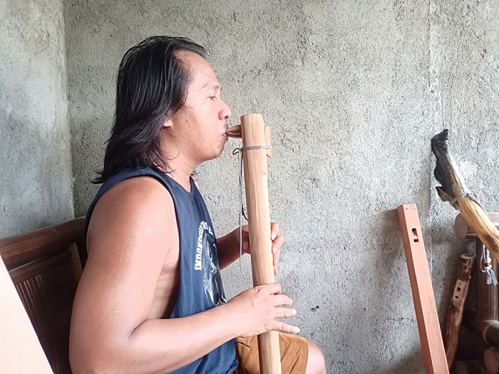 BERKARYA: Robi Akbar sedang mengetes bunyi&nbsp;seruling buatannya di rumah produksi Juang Flutes, Sabtu (20/4). (MOH. LATIF/JPRM)