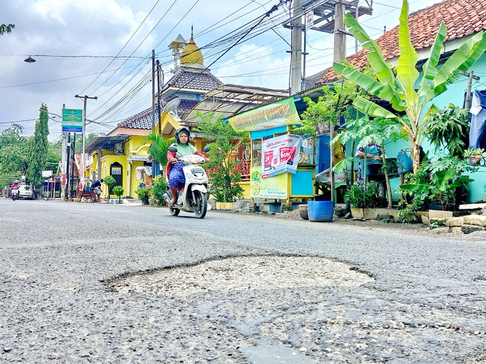 BUTUH PEMELIHARAAN: Pengendara melintas di dekat jalan berlubang, Jalan Raya Parteker, Kelurahan Parteker, Pamekasan, Sabtu (4/5). (LAILIYATUN NURIYAH/JPRM)