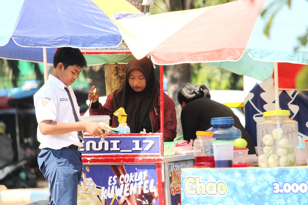 EKONOMI MIKRO: Siswa SMA membeli produk UMKM di Jalan Soekarno-Hatta, Bangkalan, Selasa (7/5). (VIVIN AGUSTIN HARTONO/JPRM)