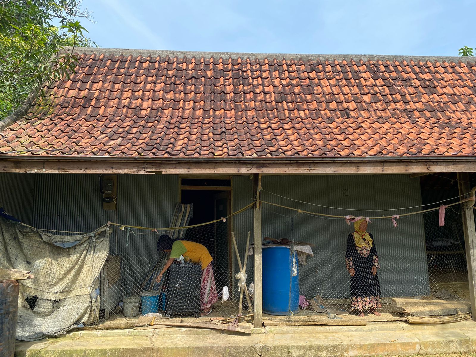 DINDING SENG: Hotijah (kanan) berdiri di teras depan rumahnya di Desa Lergunong, Kecamatan Klampis, Bangkalan, Minggu (2/6). (AYU LATIFAH/JPRM)