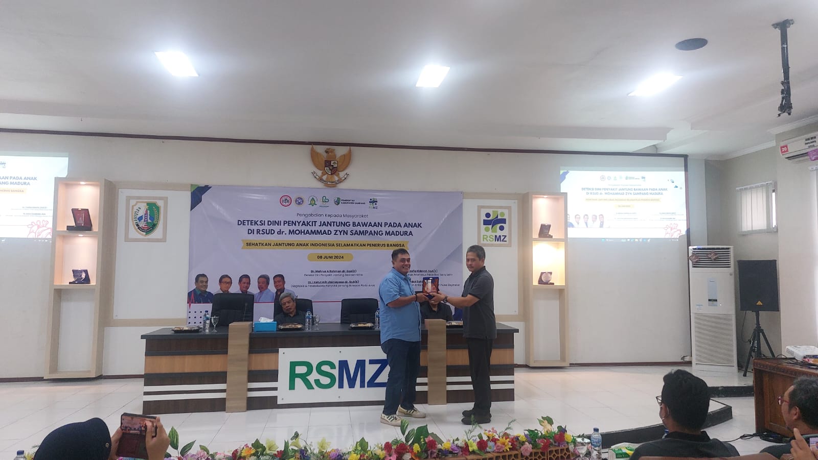 SIMBOLIS: Direktur RSUD Mohammad Zyn Sampang Agus Akhmadi menerima cenderamata dari Ketua Pelaksana Pengabdian Masyarakat I Ketut Alit Utamayasa di aula RSMZ Sampang. (JUNAIDI PONDIYANTO/JPRM)