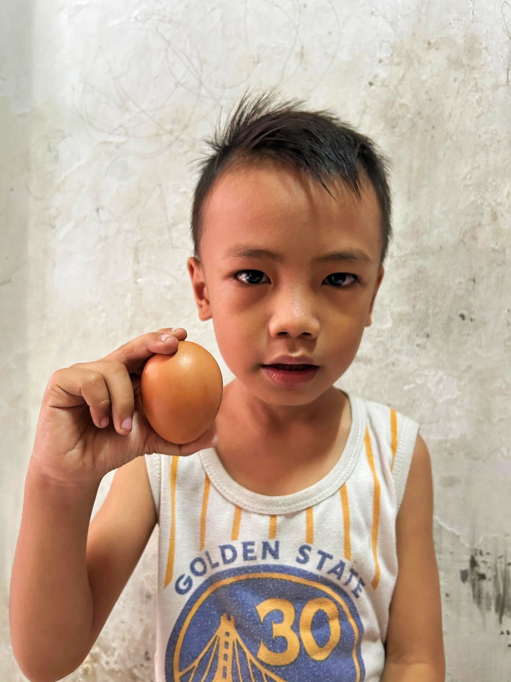 SEHAT: Seorang anak menunjukkan telur di Jalan Jokotole, Bangkalan, Jumat (7/6). (VIVIN AGUSTIN HARTONO/JPRM)
