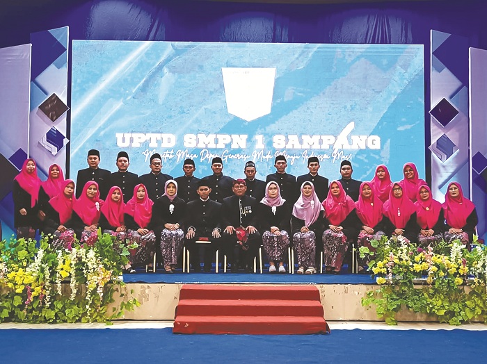 SEMANGAT: Kepala SMP Negeri 1 Sampang Teguh Suparyanto (pakai belangkon) berfoto bersama dengan guru dalam acara wisuda siswa di Gedung PKPRI Sampang Senin (10/6). (SMPN 1 SAMPANG UNTUK JPRM)