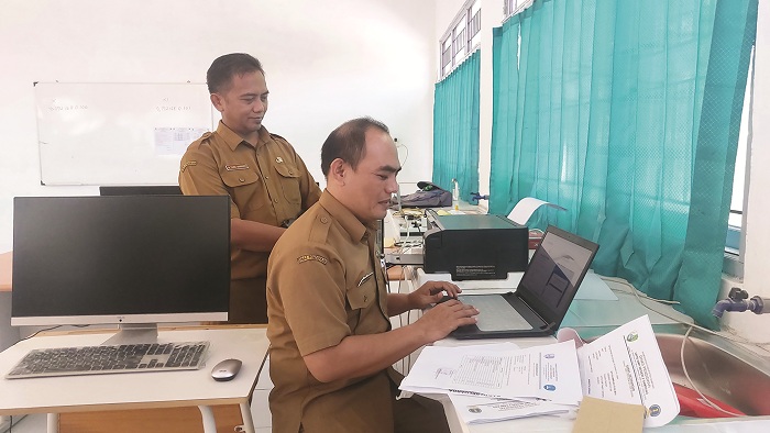 MENYAMBUT SISWA BARU: Kepala SMA Negeri 4 Sampang Moh. Farid Siswandy (berdiri) mengecek tenaga operator PPDB di sekolahnya Selasa (11/6). (JUNAIDI PONDIYANTO/JPRM)