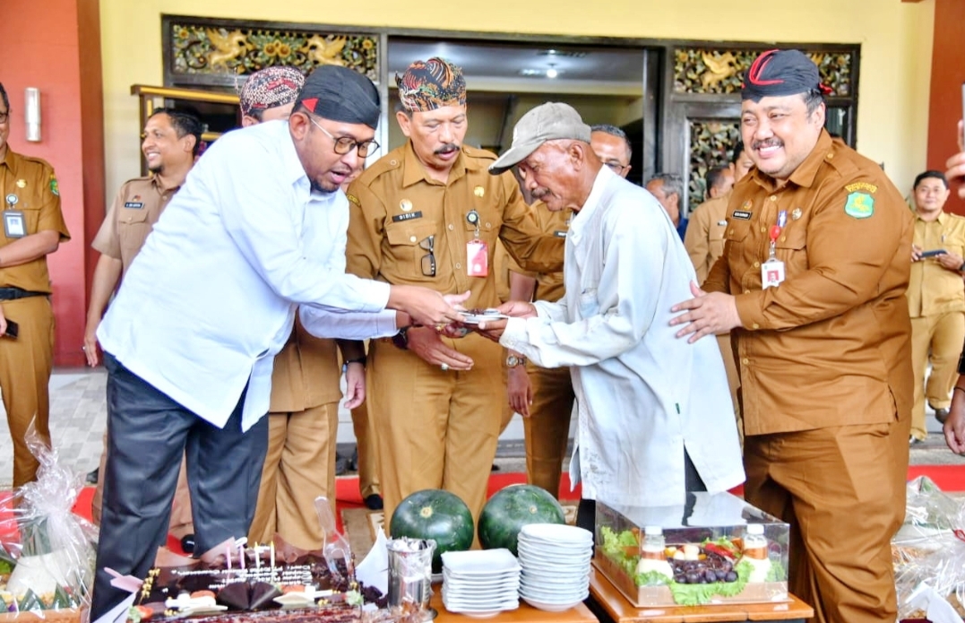 GEMBIRA: Bupati Sumenep Achmad Fauzi Wongsojudo memberikan kue kepada tukang becak saat perayaan ulang tahun ke-45 di halaman gedung pemkab, Selasa (21/5).