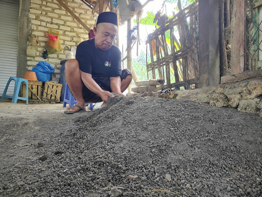 TEKUN: Fauzi mengaduk pupuk organik buatannya di Desa Galis, Kecamatan Galis, Pamekasan, Minggu (23/6). (LAILIYATUN NURIYAH/JPRM)