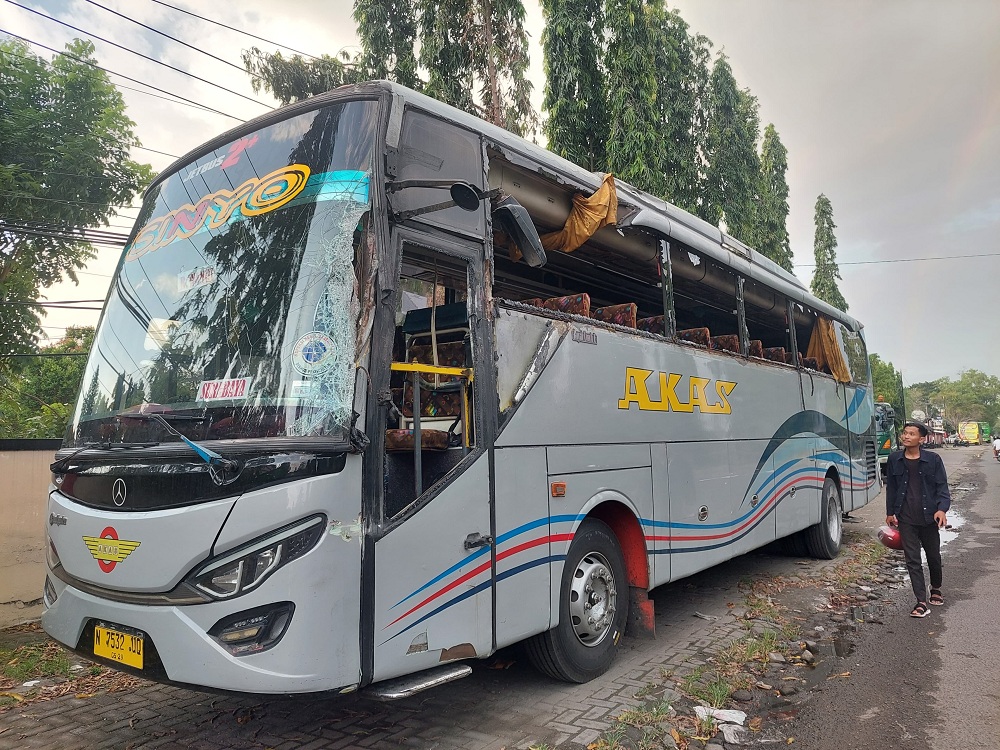 RUSAK: Seorang warga berjalan di samping bus AKAS IV &rdquo;Sinyo&rdquo; N 7532 UQ di Polres Bangkalan, Selasa (25/6). (ZEINAL ABIDIN/JPRM)