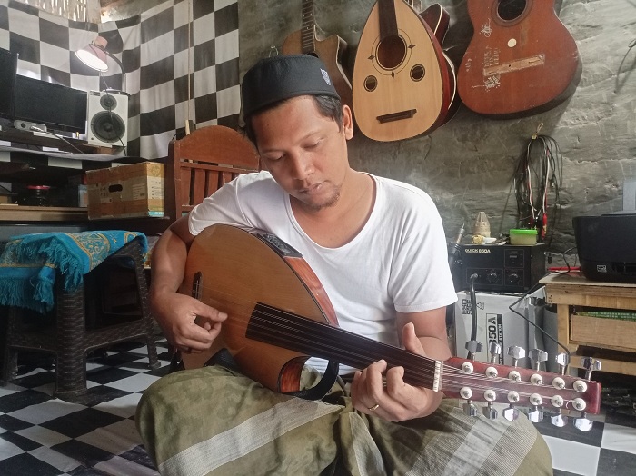 BERKARYA: Mohammad Khalili memainkan semi oud, salah satu hasil karyanya, di Desa Rombiya Barat, Kecamatan Ganding, Sumenep, Sabtu (22/6). (MOH. LATIF/JPRM)