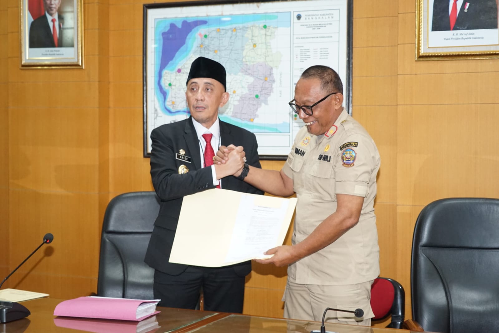 MENDAPAT KEPERCAYAAN: Pj Bupati Bangkalan Arief M. Edie (kiri) menyerahkan SK Plh Sekkab kepada Irman Gunadi di kantor pemkab, Senin (1/7).