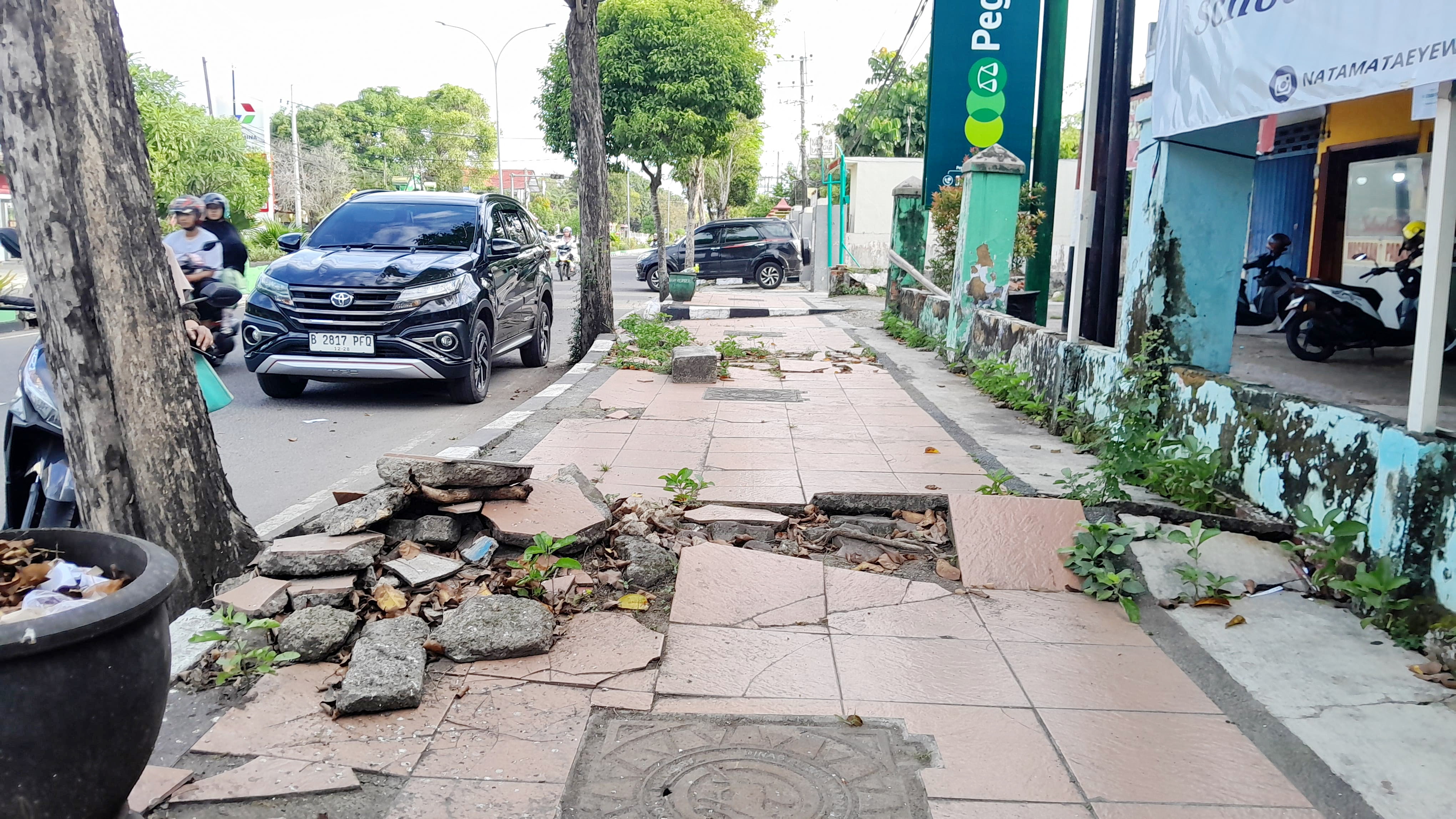 TERBENGKALAI: Kendaraan roda empat terparkir di sekitar trotoar rusak di Jalan Soekarno-Hatta, Bangkalan, Rabu (3/7). (KHOLIL RAMLI/JPRM)