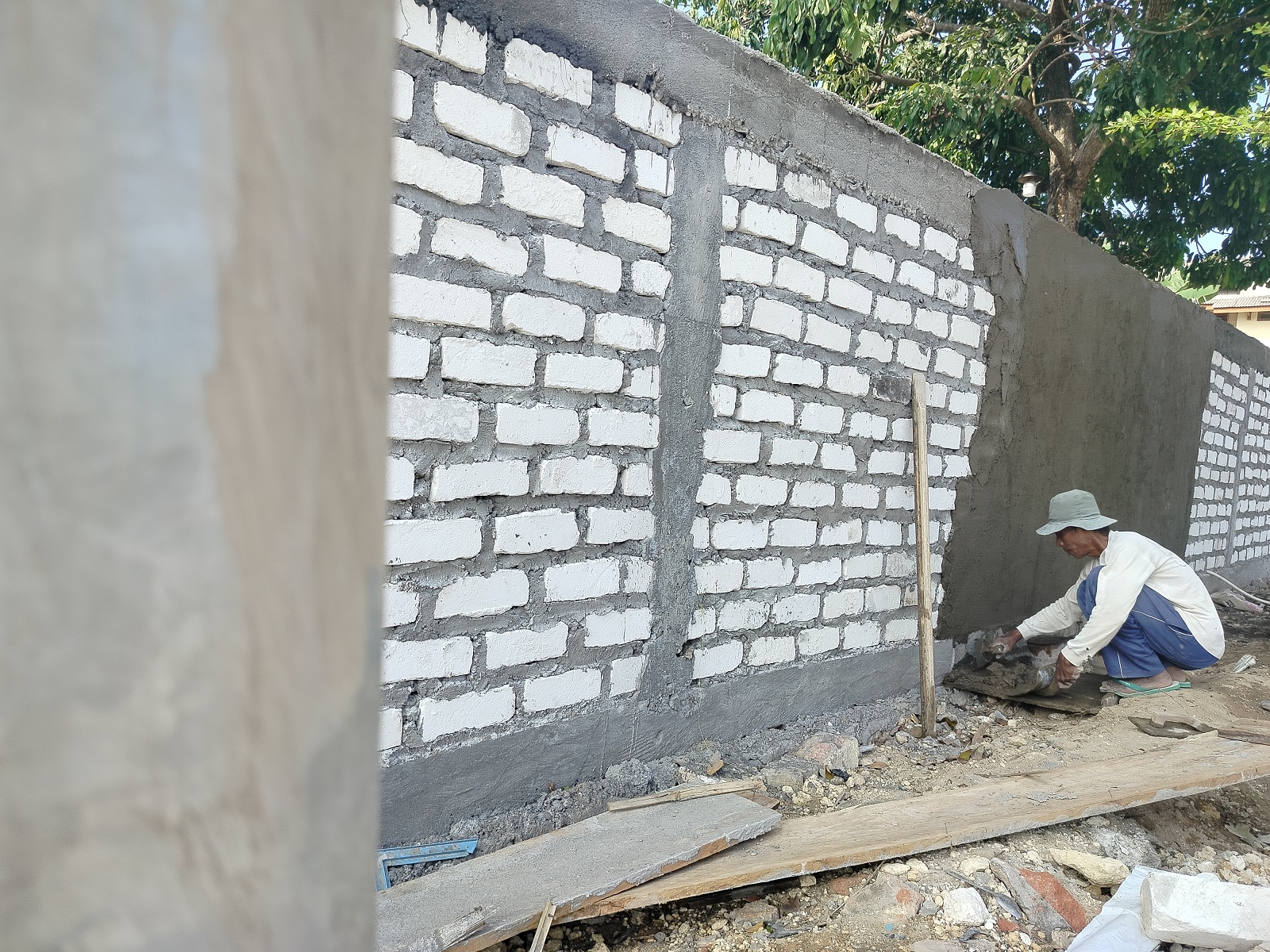 PROSES: Pekerja sedang mengecor dinding pagar tembok di sentra PKL Sae Rassa, Kelurahan Bugih, Pamekasan, Minggu (7/7).