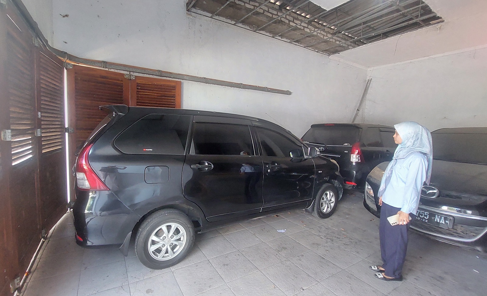 LELANG ASET: Salah seorang pegawai PT GSM melihat satu unit mobil Avanza yang dilelang di parkiran kantornya, Senin (8/7).