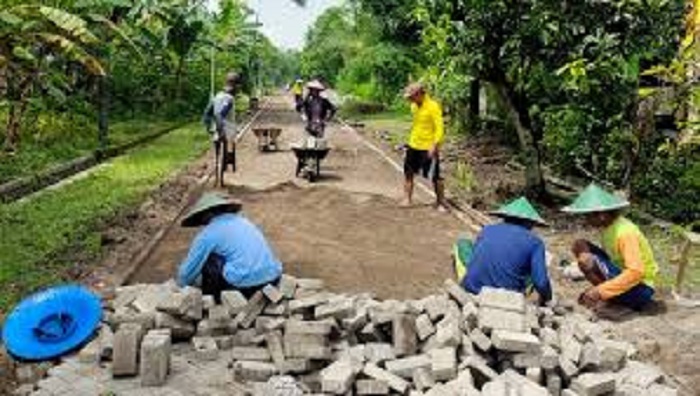 Warga bergotong royong memasang paving. (RADAR MADIUN)