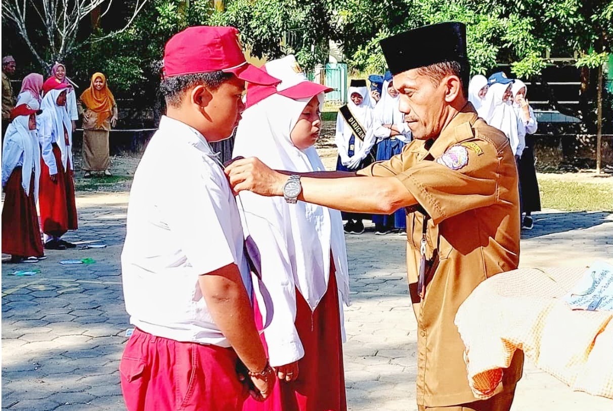 HARAPAN MASA DEPAN: Kepala UPTD SMPN 2 Sepulu Sunarto memasang tanda peserta MPLS, Senin (15/7).