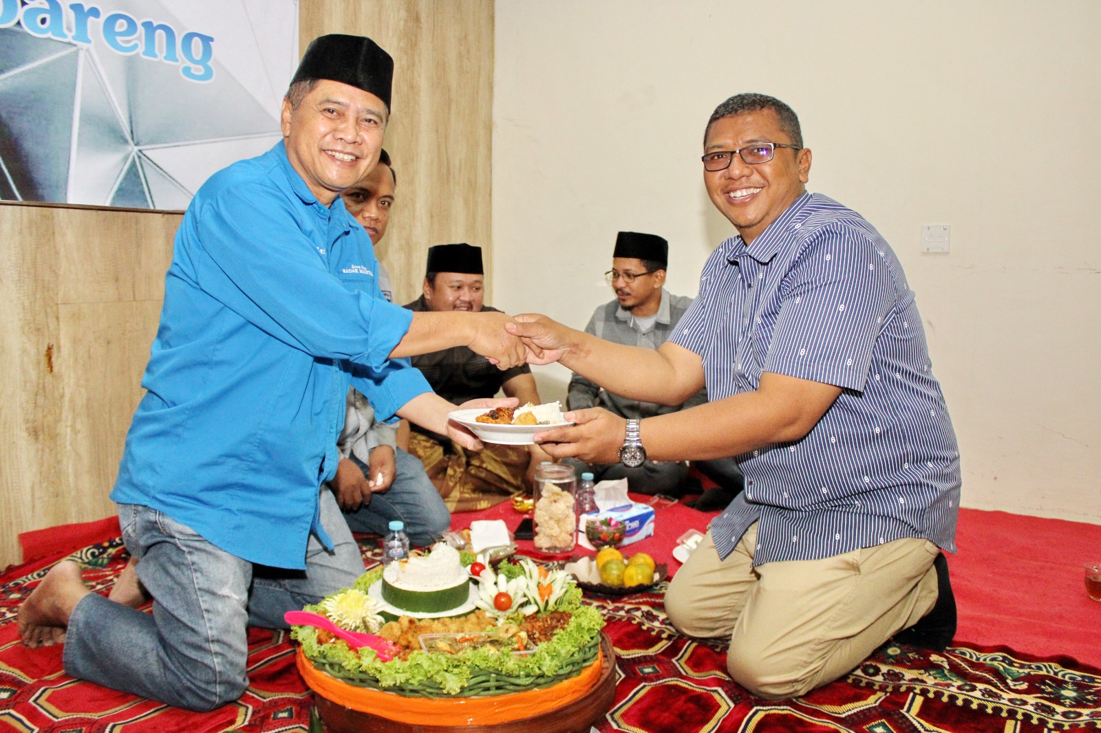 SALING SUPPORT: Direktur JPRM Abdul Aziz memberikan potongan tumpeng kepada Ketua Bawaslu Bangkalan Ahmad Mustain Saleh di kantor pusat JPRM, Sabtu (27/7). (VIVIN AGUSTIN HARTONO/JPRM)