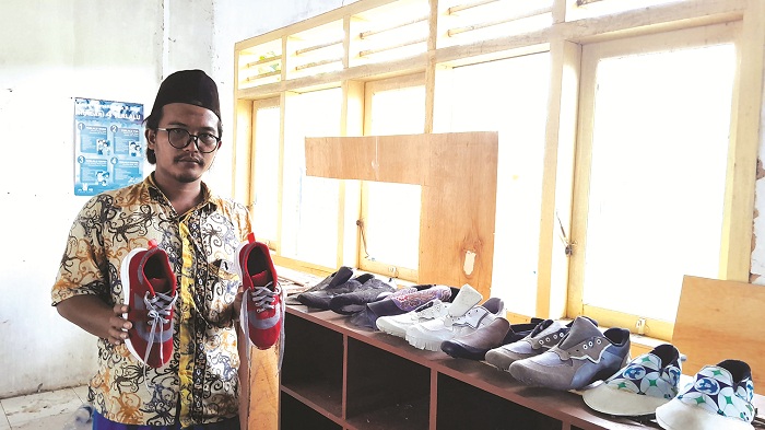 KREATIF: Zubair Ali Mortadho menunjukkan hasil produksi sepatu yang dibuatnya di warga Desa Seddur, Kecamatan Pakong, Pamekasan, Sabtu (3/8). (M. KHOLIL RAMLI/JPRMc)