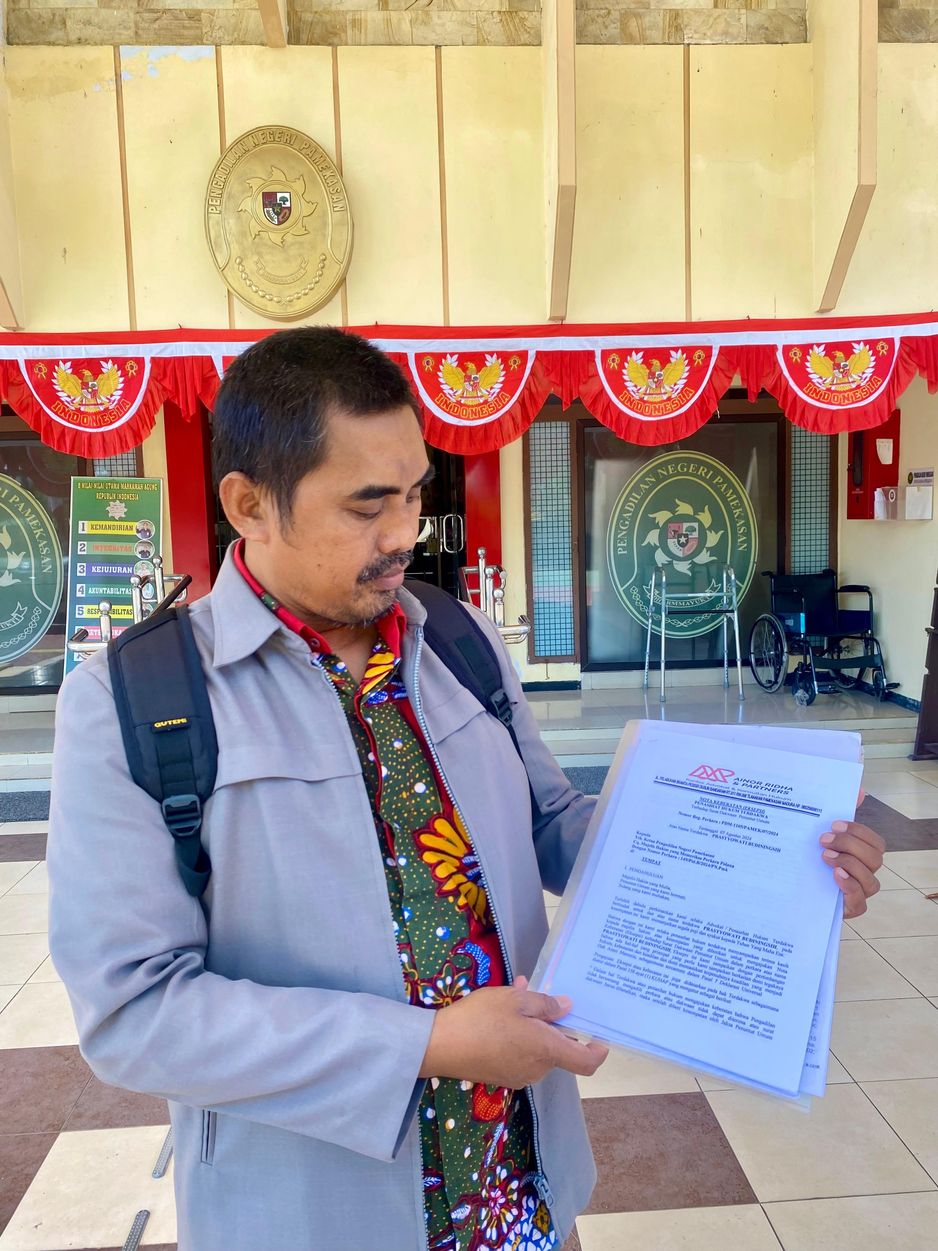 MELAWAN: Ainor Ridho selaku penasihat hukum Prastyowati Budiningsih menunjukkan berkas eksepsi setelah sidang di PN Pamekasan, Rabu (15/8). (MOH. IQBAL AFGANI/JPRM)