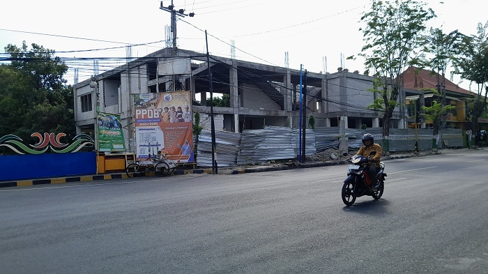 MANGKRAK: Pengendara melintas di dekat gedung perpustakaan dan kearsipan Pamekasan Minggu (18/8). (M. KHOLIL RAMLI/JPRM)