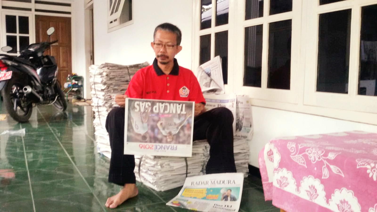 PELANGGAN SETIA: H. Ali Maksum sedang membaca koran JPRM di rumahnya, Jalan Dirgahayu Gg V/46 Kelurahan Bugih, Pamekasan. (SUBHAN/JPRM)