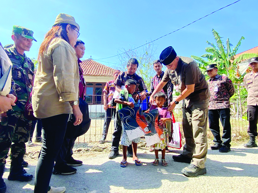 PEDULI: Pj Bupati Bangkalan Arief M. Edie memakaikan tas kepada M dan YB di Desa Sukolilo Barat, Kecamatan Labang, Kamis (29/8). (JUPRI/JPRM)
