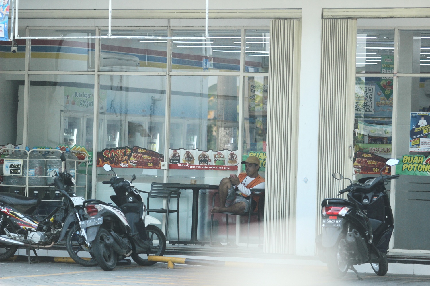 SANTAI: Seorang jukir istirahat di salah satu toko modern, Jalan Soekarno-Hatta, Bangkalan, Minggu (1/9). (VIVIN AGUSTIN HARTONO/JPRM)