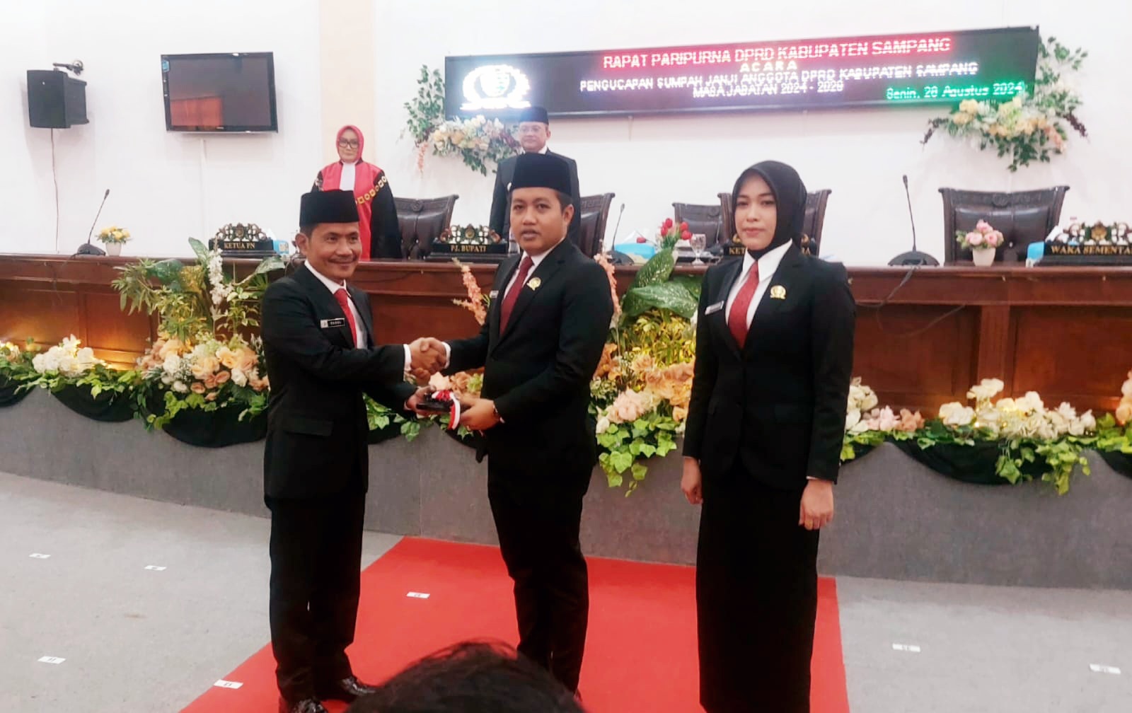 SIMBOLIS: Ketua sementara DPRD Sampang Rudi Kurniawan (tengah) saat menerima penyerahan palu pimpinan dari Ketua DPRD Sampang 2019-2024 Fadol di kantor dewan Senin (26/8). (JUNAIDI PONDIYANTO/JPRM)