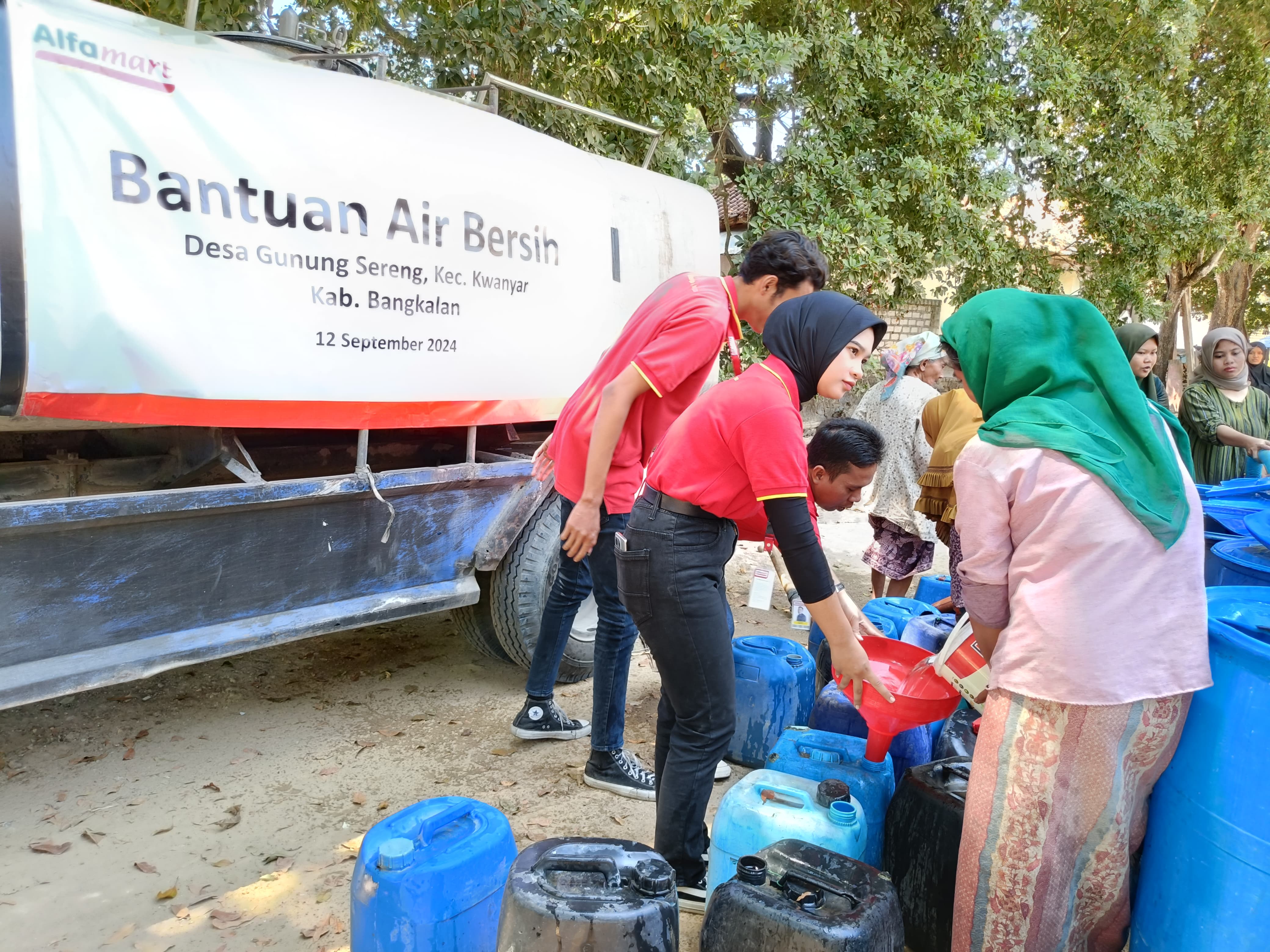 KEKERINGAN: Warga Bangkalan mendapatkan bantuan air bersih dari Alfamart.