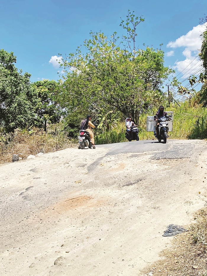 RUSAK: Pengendara melaju pelan saat melewati ruas jalan di Desa Tlontoraja, Kecamatan Pasean, Pamekasan. (AYU LATIFAH/JPRM)