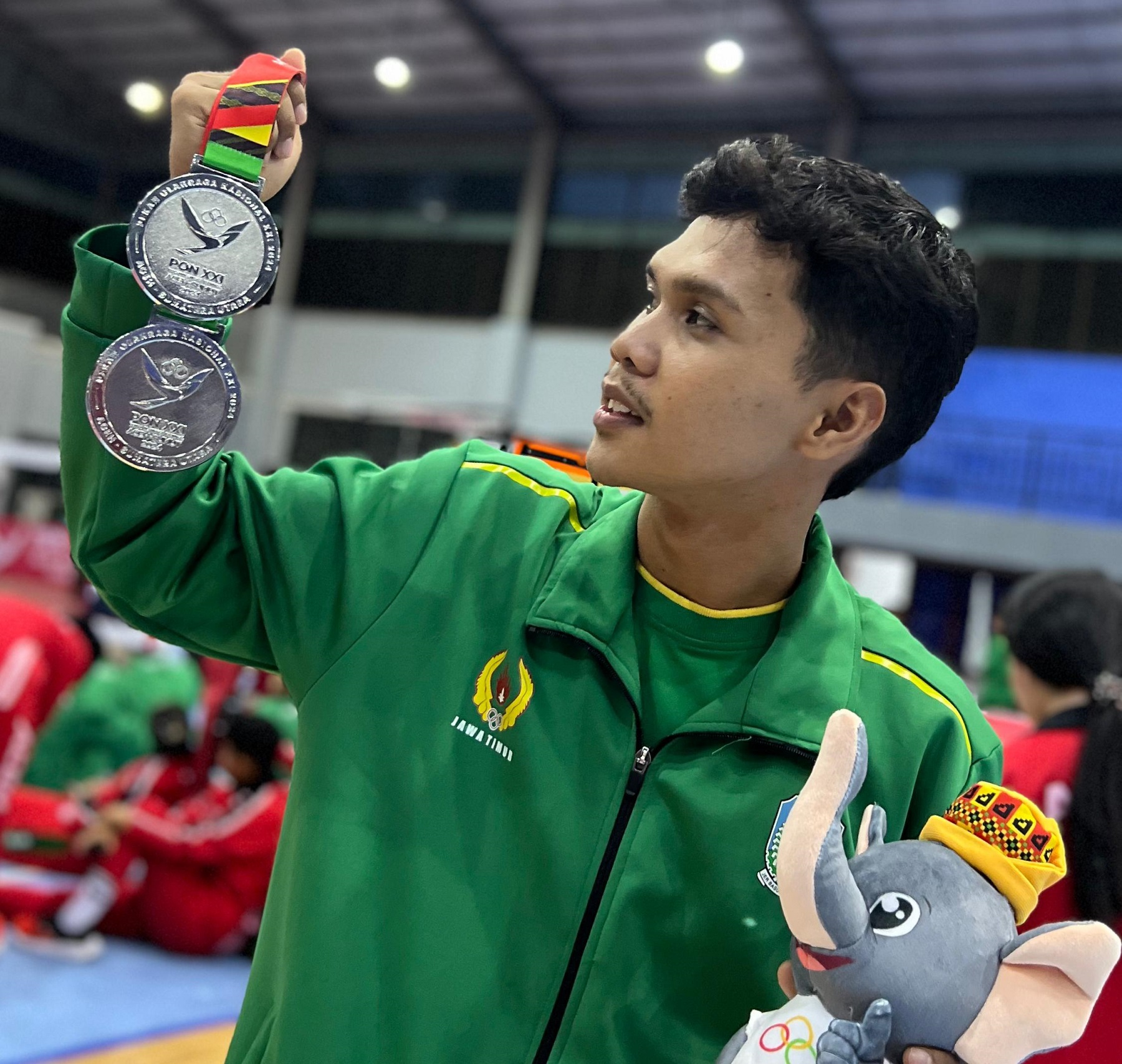 MEMBANGGAKAN: Atlet PSTI Sumenep Zakariya Abil Rasyid memegang medali perak yang diperoleh timnya saat berlaga mewakili tim sepak takraw Jatim di PON XXI Aceh-Sumut pada Minggu (15/9).
