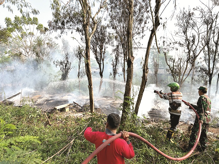 RATA DENGAN TANAH: Petugas Damkar Satpol PP Bangkalan dibantu TNI memadamkan kandang ayam yang terbakar di Desa Kramat Kamis (19/9). (VIVIN AGUSTIN HARTONO/JPRM)